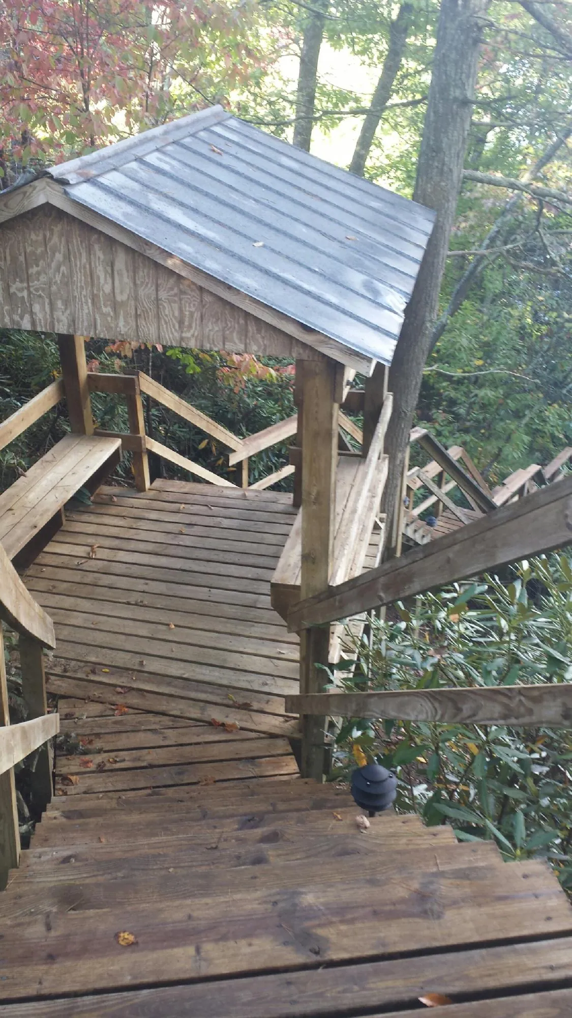 Metal roofed shelter over wooden steps on a wooded walkway — Skylight Repair & Installation work by our crew in Saint George